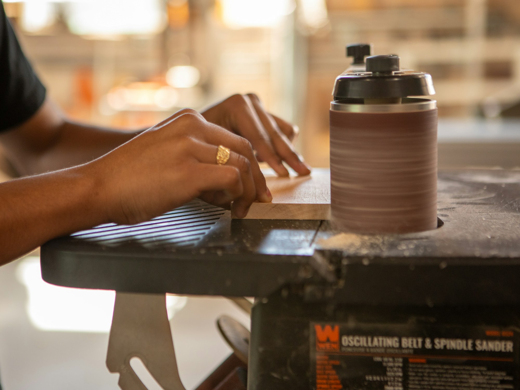 Hands finishing a piece of wood in the workshop